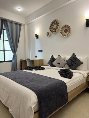 a bedroom with a large white bed with black pillows at Ahiva Village in Fulhadhoo