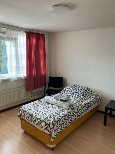Un pequeño dormitorio con una cama y una silla. en Expats House 4 Etten-Leur, en Etten-Leur