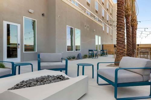 a lobby with chairs and a table and palm trees at Cambria Hotel El Centro - Imperial in El Centro