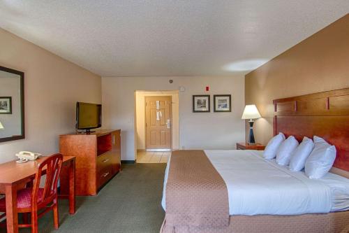 a hotel room with a bed and a desk and a television at Park Tower Inn in Pigeon Forge