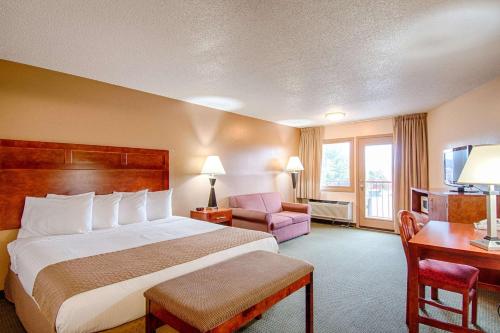 a hotel room with a bed and a chair and a desk at Park Tower Inn in Pigeon Forge