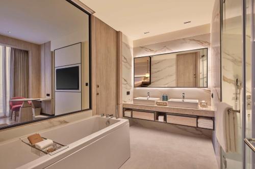 a bathroom with a tub and two sinks and a television at Hilton Gurugram Baani City Centre in Gurgaon