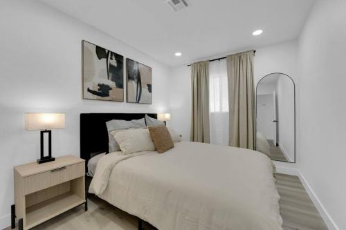a white bedroom with a bed and a mirror at Vegas Bliss near The Strip - Pet & Family Friendly in Las Vegas