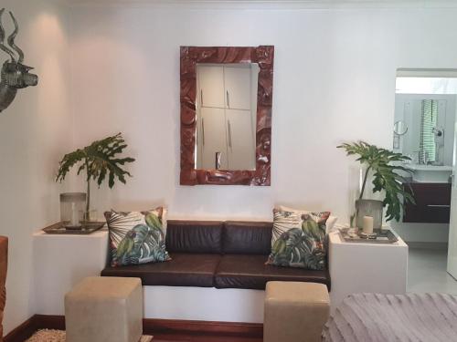 a living room with a couch and a mirror at De Kloof Heritage Estate and Wellness in Swellendam