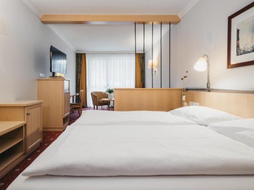 a hotel room with a large bed and a desk at Sporthotel Royer in Schladming