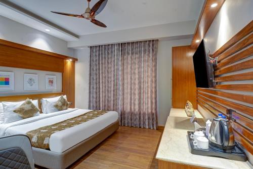 a hotel room with a bed and a flat screen tv at Hotel The Pearl, City Center - Traveler's Choice Award Winner for 2025 in New Delhi