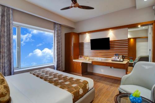 a hotel room with a bed and a desk and a tv at Hotel The Pearl, City Center - Traveler's Choice Award Winner for 2025 in New Delhi