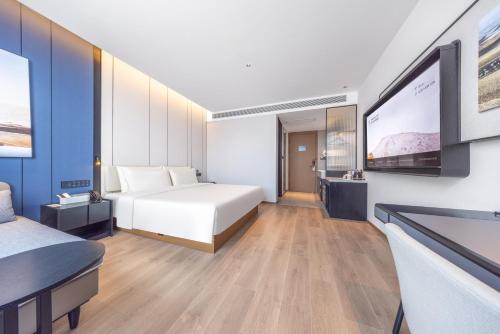 a hotel room with a bed and a flat screen tv at Atour Hotel Maitreya Avenue Huquan Ecological Park in Mile