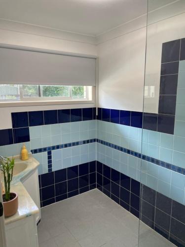 baño con paredes de azulejos azules y ducha. en 3BR Comfy Home, Gym & Garden in The Gap, en The Gap
