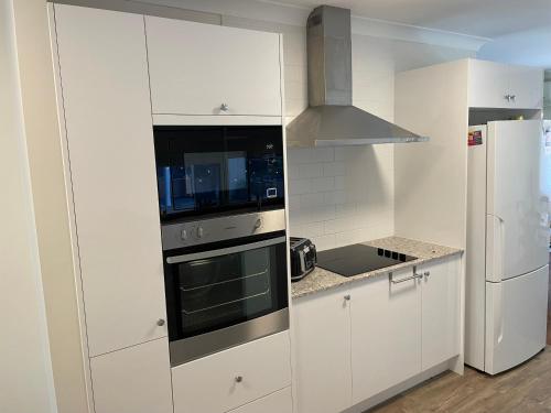 Una cocina blanca con estufa y refrigerador. en 3BR Comfy Home, Gym & Garden in The Gap, en The Gap