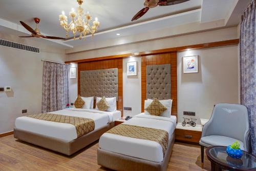 a bedroom with two beds and a table and a chandelier at Hotel The Pearl, City Center - Traveler's Choice Award Winner for 2025 in New Delhi