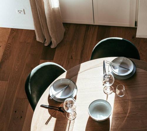 a wooden table with plates and wine glasses on it at Hidden Retreats The Alpstyle in Frutigen