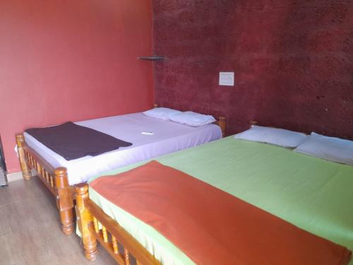 two beds in a room with red walls at Aisiri comforts beach stay and cafe in Gokarn