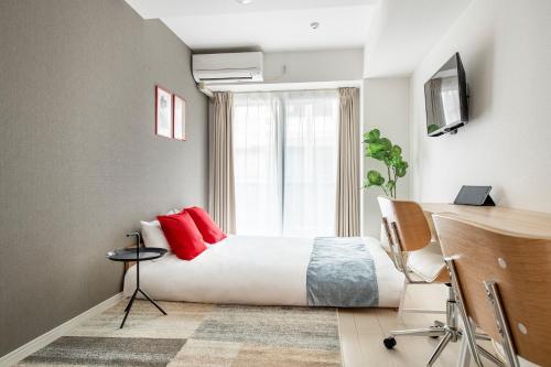 a bedroom with a bed with red pillows and a window at GRANDE Morisita in Tokyo