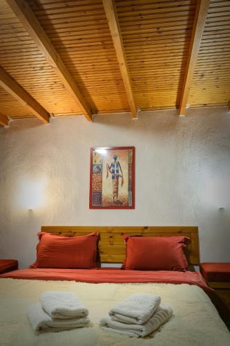 a bedroom with a large bed with red pillows at Konaki inn in Palaios Agios Athanasios