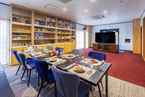 Un comedor con mesa y sillas y un televisor. en BBQ可能 露天風呂付き 麻雀 ビリヤード 卓球も可能な最大12名の一棟貸し KOEI HOUSE in KANNA, en Ginoza