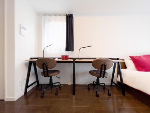 a desk in a bedroom with two chairs and a bed at GRANDE Morisita in Tokyo
