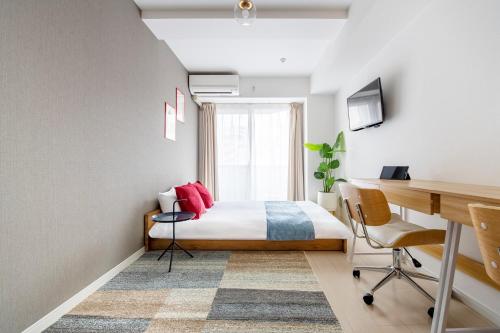 a bedroom with a bed with red pillows and a desk at GRANDE Morisita in Tokyo
