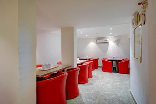 a room with red chairs and tables in a restaurant at Hotel The Pearl, City Center - Traveler's Choice Award Winner for 2025 in New Delhi