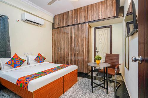 a bedroom with a bed and a table and a door at FabHotel Eminent Suites Banjara Hills - Nr LV Prasad Institute in Hyderabad
