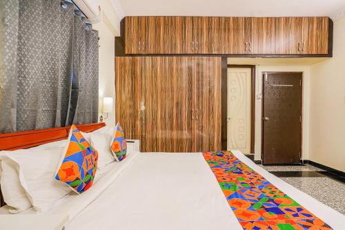 a bedroom with a large white bed with colorful pillows at FabHotel Eminent Suites Banjara Hills - Nr LV Prasad Institute in Hyderabad