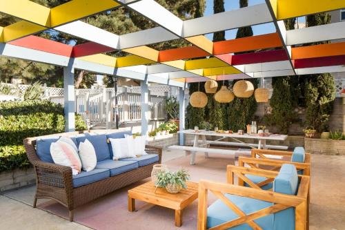 a patio with a blue couch and chairs under a colorful roof at Kokomo by AvantStay Bayside Getaway w Fire Pit Large Outdoor Patio in San Diego