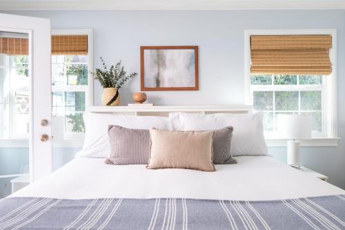 a white bedroom with a large white bed with pillows at Kokomo by AvantStay Bayside Getaway w Fire Pit Large Outdoor Patio in San Diego