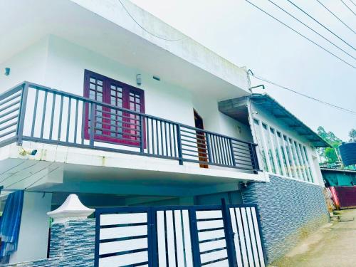 a white house with a balcony and a staircase at Rainbow mist Homestay in Munnar
