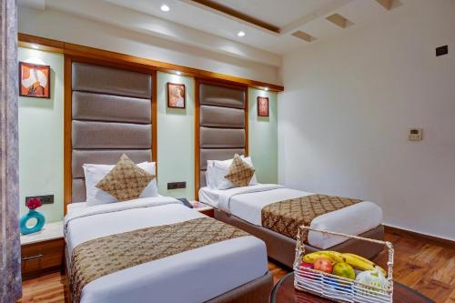 two beds in a room with a basket of fruit at Hotel The Pearl, City Center - Traveler's Choice Award Winner for 2025 in New Delhi