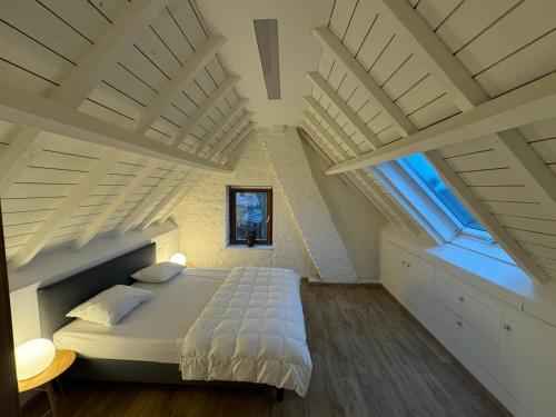 a bedroom with white ceilings and a large bed at De Veldmuis, met mooie speelhoek en speelhuis in Koksijde