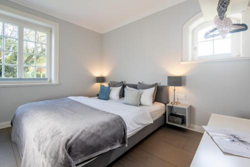a white bedroom with a large bed and a window at Marie - Gartensuite in Archsum