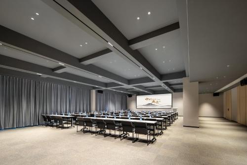 a conference room with tables and chairs and a screen at Atour Hotel Tengchong Wenxing Building in Tengchong