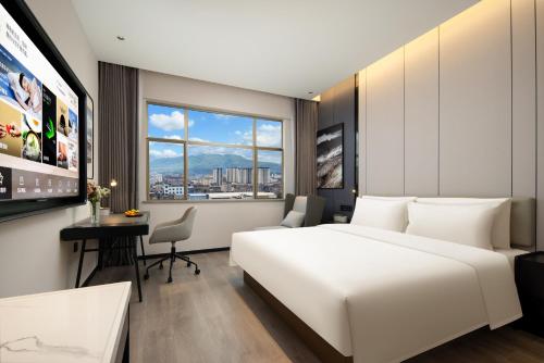 a bedroom with a large white bed and a desk at Atour Hotel Tengchong Wenxing Building in Tengchong