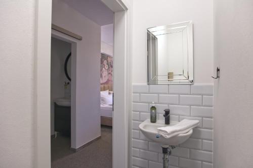 a white bathroom with a sink and a mirror at Villa Delange in Landau in der Pfalz