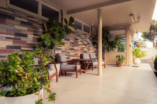 a patio with chairs and tables and a brick wall at Paradise Motel Busselton in Busselton