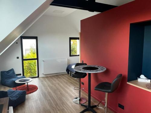 Cette chambre dispose d'un mur rouge, d'une table et de chaises. dans l'établissement Ty Nid d'Amour Ty Matlo, à Névez