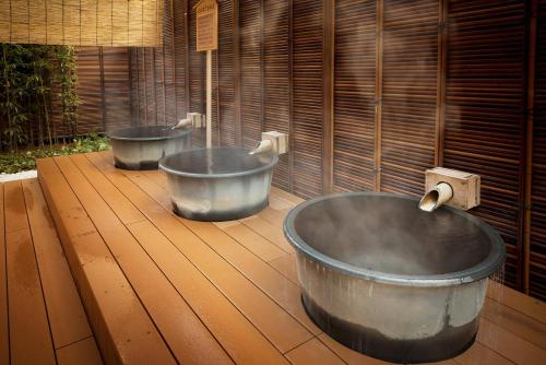 two metal tubs sitting on top of a wooden deck at Arima Kirari in Kobe