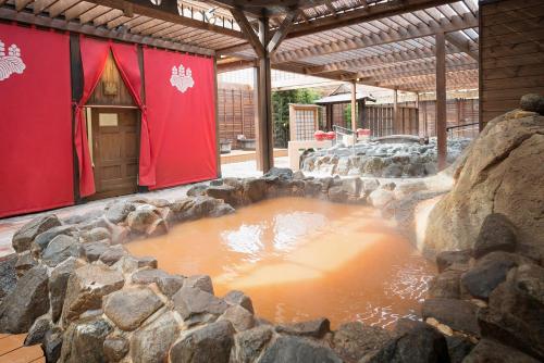 a large pool of brown liquid in a pond with rocks at Arima Kirari in Kobe