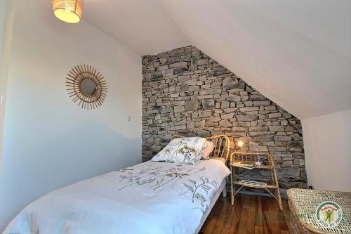 a bedroom with a stone wall and a bed at Les camelias in Plouézec