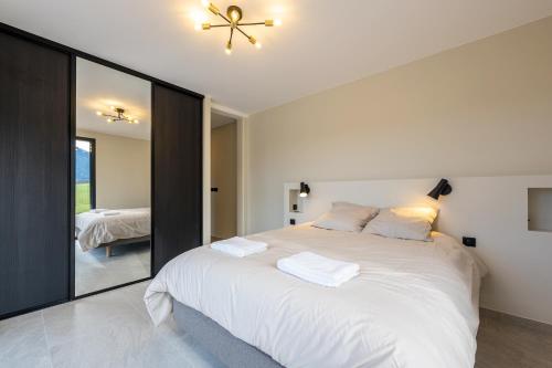 a bedroom with a large white bed and a mirror at Chalet Rossanaz in La Motte-en-Beauges