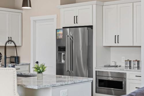 a kitchen with white cabinets and a stainless steel refrigerator at Lakeside Serenity by AvantStay Lakefront Newly Built Deck w Views in White Haven