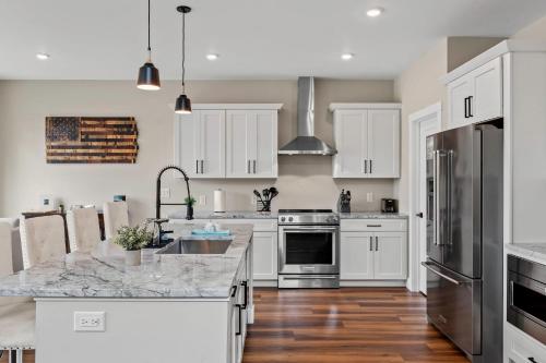 a kitchen with white cabinets and stainless steel appliances at Lakeside Serenity by AvantStay Lakefront Newly Built Deck w Views in White Haven
