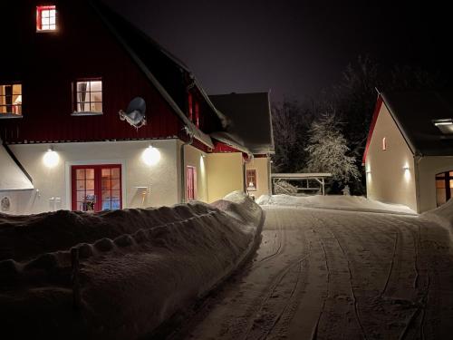 a snow covered street in front of a house at night at Zur Bergwiese 5 Sterne Appartementhaus in Fürstenau