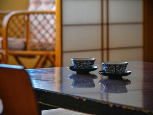 two cups sitting on top of a wooden table at Hokuriku Fukui Awara Onsen Mimatsu in Awara