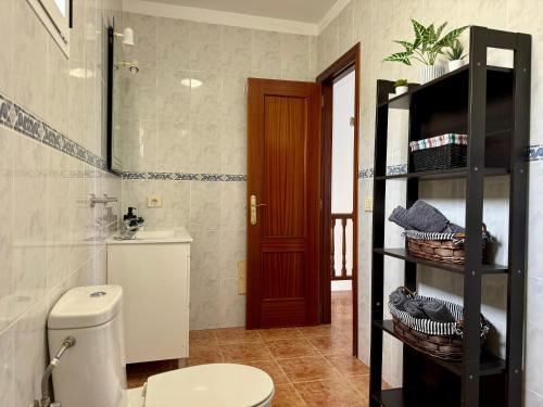 a bathroom with a toilet and a shelf with towels at Casa Marina by Vulcano Homes in Arrieta