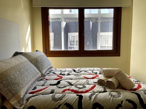 a bed with two towels on it with a window at Apartamento 3 habitaciones en Plaza de España 6PAX in Vigo