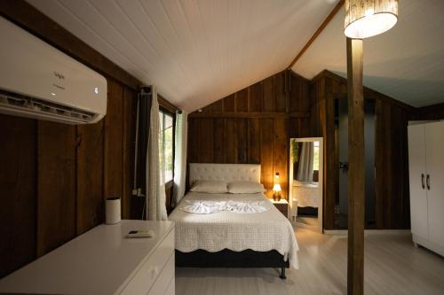 a bedroom with a bed in a room with wooden walls at Casa Alegria da Ilha in Paranaguá