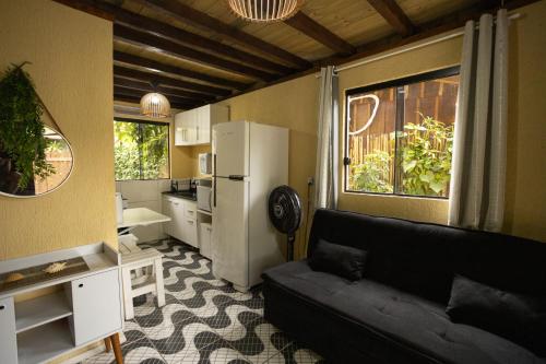 a living room with a black couch and a kitchen at Casa Alegria da Ilha in Paranaguá