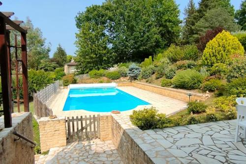 une piscine dans un jardin avec un mur en pierre dans l'établissement Domaine-Paysage-Piscine-Sarlat, à Sarlat-la-Canéda