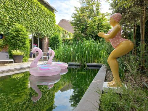a statue of a girl standing next to three pink swans at B&B La Corderie in Hamme